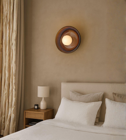 Architectural orb wall lamp with circular backplate providing soft ambient lighting in a modern bedroom
