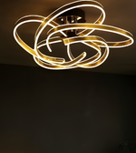 Modern ceiling light fixture with gold finish on a dark background