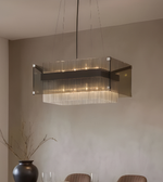 Modern pendant light fixture hanging in a room with a vase and chairs.
