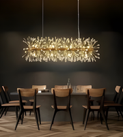 Modern chandelier hanging above a dining table with chairs in a dimly lit room.