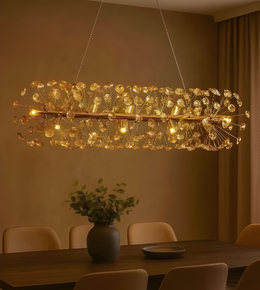 Modern chandelier hanging above a dining table with chairs and a vase of flowers.