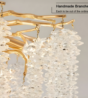 Gold branch-like chandelier with crystal elements on a gray background