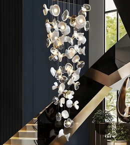 Modern chandelier hanging in a stylish interior setting with stairs and plants.