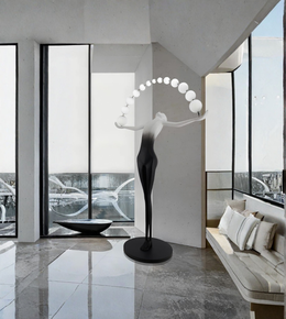 Modern interior with a sculpture and floor lamp in a room with large windows.