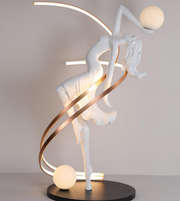 Decorative table lamp with a white figure and gold spiral on a neutral background