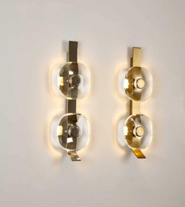 Two modern wall sconces with gold and glass design on a white wall.