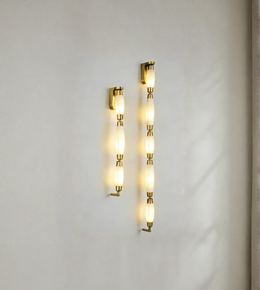  Gold  wall sconces with glass shades on a light gray wall.