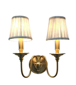 Pair of gold wall sconces with fabric shades on a white background