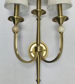 Brass wall sconce with three lampshades on a white background