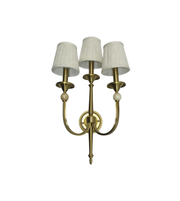 Brass wall sconce with three white lampshades on a white background