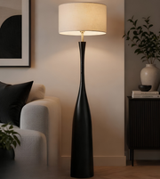 Black floor lamp in a living room setting with a beige sofa and decorative items.