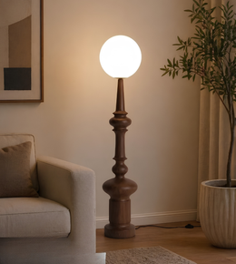 Floor lamp with wooden base and white globe shade in a living room setting.