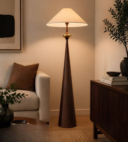 Modern floor lamp in a living room setting with a couch and decorative items.