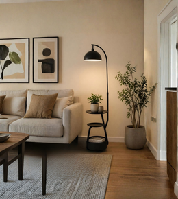 Living room with a beige sofa, coffee table, floor lamp, and decorative plants.