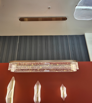 Crystal chandelier hanging above a red wall with decorative items.