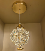 Decorative ceiling light fixture with gold finish and crystal-like design on a beige wall.