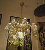 Gold and crystal chandelier hanging in a room with mirrors.