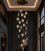 Modern chandelier hanging in a dark room with large windows