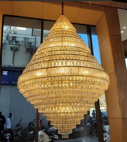 Large crystal chandelier hanging indoors with people and scooters in the background