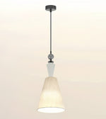 A modern pendant light fixture with a black metal rod, a white geometric accent, and a textured cream-colored fabric shade, shown against a plain off-white background.