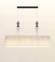 A modern rectangular pendant light fixture with a wide, tapered beige fabric shade, suspended from a black horizontal bar with two clear glass cone drops and dark gray spherical accents.