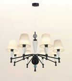 A modern 9-light chandelier with a black metal frame, textured off-white drum shades, and white glass cone accents, suspended from a ceiling.