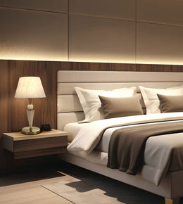 A modern bedroom interior featuring a bed with white linens and taupe pillows, a matching upholstered headboard, a floating wood nightstand with a white table lamp, and warm ambient lighting against a wood-paneled wall.