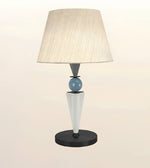 A modern table lamp with a tapered beige fabric shade, a light blue glass sphere, a white cone-shaped base, and a black circular base, shown against a plain light beige background.