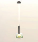 A modern single pendant light with a brushed metal canopy and rod, featuring a frosted glass shade that glows with a warm yellow light, set against a soft beige gradient background.