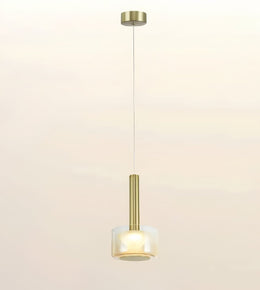 A modern single pendant light with a brushed gold metal cylinder stem and a frosted white glass shade, suspended by a thin cord against a warm off-white background.
