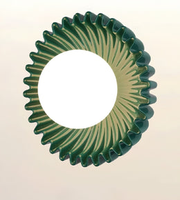 A round, fluted decorative bowl or dish with a deep green and cream sunburst pattern, shown against a plain light beige background.