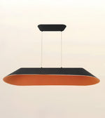 A modern rectangular pendant light with a black top canopy and frame, and a warm orange interior, suspended by thin cables against a plain off-white background.