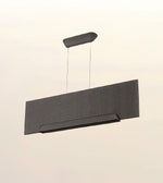 A modern rectangular pendant light fixture with a textured chevron pattern, suspended by thin cables from a matching ceiling mount against a plain off-white background.