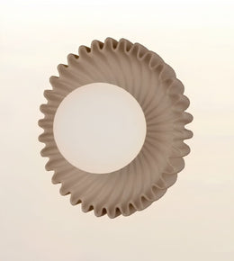 A modern circular ceiling light fixture with a textured, fluted outer rim and a frosted white central globe, shown against a plain off-white background.
