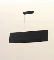 A modern rectangular black pendant light with a subtle herringbone texture, suspended by two thin cables from a matching curved ceiling mount against a plain off-white background.