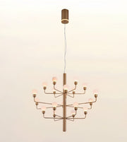 A modern multi-light chandelier with a brushed brass finish and glowing frosted glass globe bulbs, suspended against a plain off-white background.