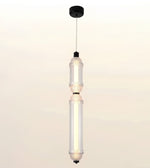 A modern two-light linear pendant ceiling fixture with clear textured glass shades and black metal accents, suspended by a thin cord from a black ceiling canopy.