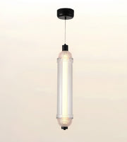 A modern cylindrical pendant light with a ribbed clear glass shade, black ceiling canopy and cord, shown against a soft off-white background.