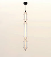 A modern multi-light linear pendant ceiling fixture with three illuminated glass cylindrical bulbs suspended vertically from a black ceiling canopy.