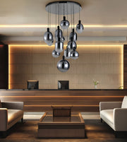 A modern multi-light chandelier with reflective silver glass globes hanging in a lobby setting with a reception desk and beige seating.