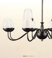 A multi-arm chandelier with a dark bronze metal frame and textured clear glass shades, shown against a plain beige background.
