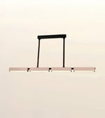A modern linear LED pendant light with a matte black frame and horizontal bar, suspended against a plain off-white background.