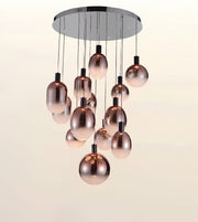 Modern chandelier with a circular chrome ceiling mount and multiple hanging rose-gold metallic glass globes against a plain light background.