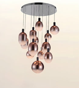 Modern chandelier with a circular chrome ceiling mount and multiple hanging rose-gold metallic glass globes against a plain light background.