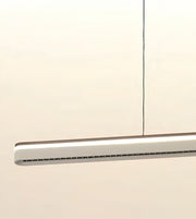 A modern linear LED pendant light with a slim rectangular silver and white body, suspended by a thin black cord against a plain off-white background.