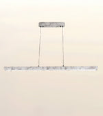 A modern linear LED pendant light with a white marble-look horizontal bar suspended by two thin black cables from a matching rectangular ceiling mount, shown against a plain beige background.