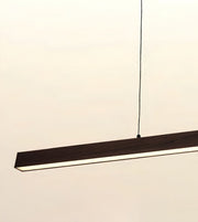 A modern linear LED pendant light with a dark wood-grain finish and a slim black suspension cord, shown against a plain off-white background.