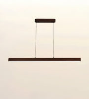 A modern linear LED pendant light with a dark brown wood-look finish and slim hanging cables, shown against a plain off-white background.