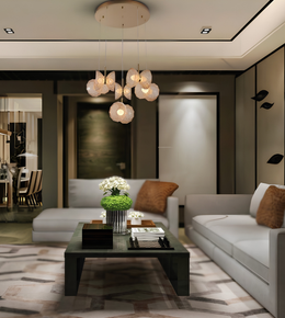 A modern living room interior featuring a multi-light pendant chandelier with white flower-shaped glass shades hanging over a dark coffee table, flanked by light gray sofas with brown accent pillows.