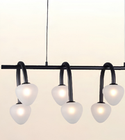 Modern black metal chandelier with six curved arms and frosted white globe shades, shown against a plain light background.